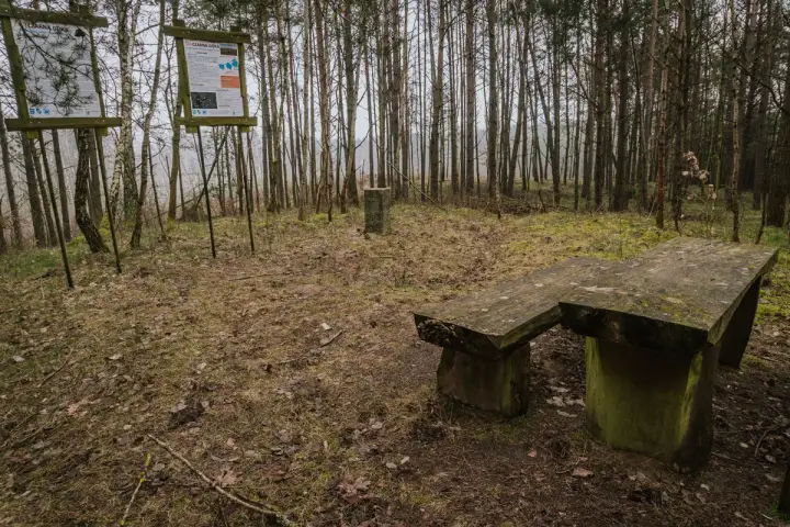 Kamienny stół i ławka w lesie, obok tablice informacyjne. Miejsce na odpoczynek podczas wędrówki po górach obkaskich.