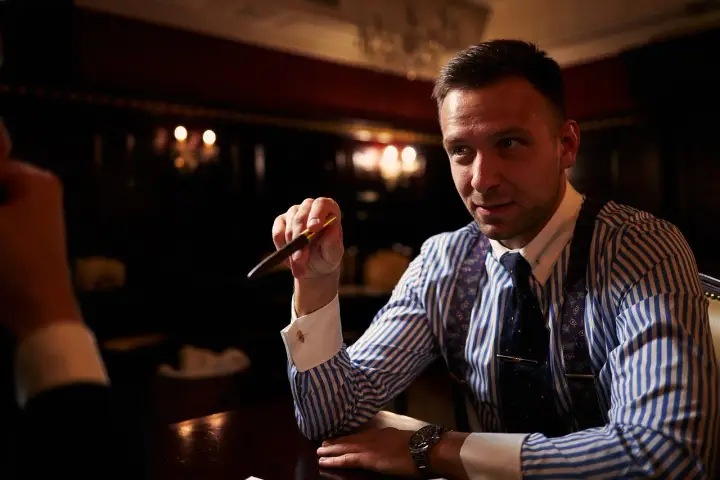 Mężczyzna w eleganckiej koszuli i krawacie trzyma pióro, zastanawiając się, ile bierze adwokat za reprezentowanie w sądzie.
