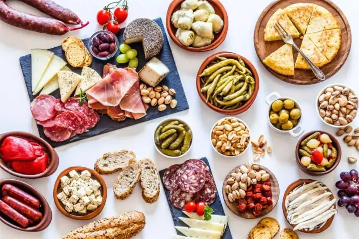 Un festin de tapas pour une pendaison de crémaillère : charcuterie, fromages, olives, cornichons, fruits secs et pain.