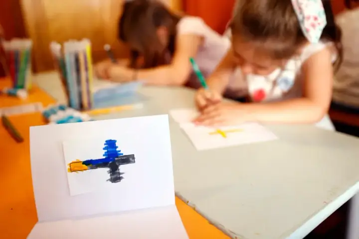 Dzieci rysują krzyże, ucząc się o religii w szkole. Na pierwszym planie symbol wiary.