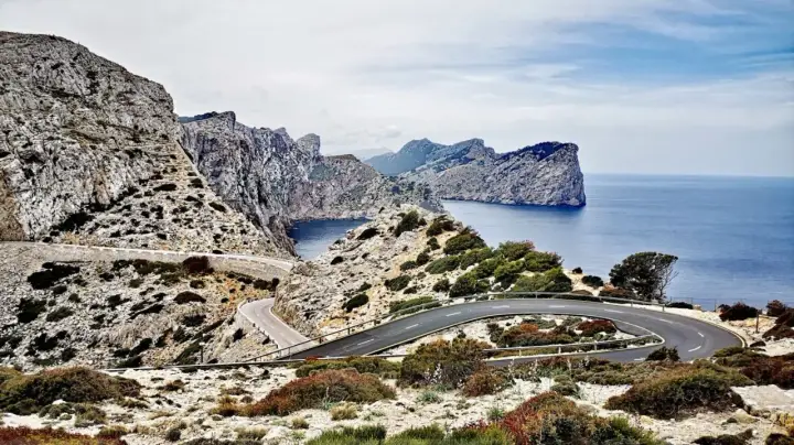 Carretera sinuosa en acantilados rocosos con vistas al mar azul. Un viaje en coche por un paisaje espectacular.