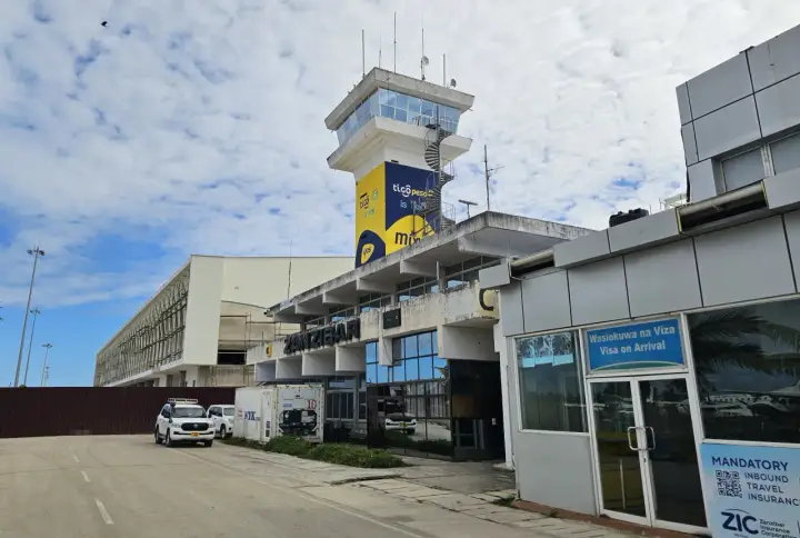 Kontrolltorn och terminalbyggnad vid Zanzibar flygplats. En vit SUV parkerad framför.