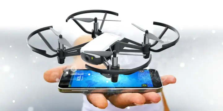 Kleine Drohne schwebt über einem Smartphone, das die tello app anzeigt.