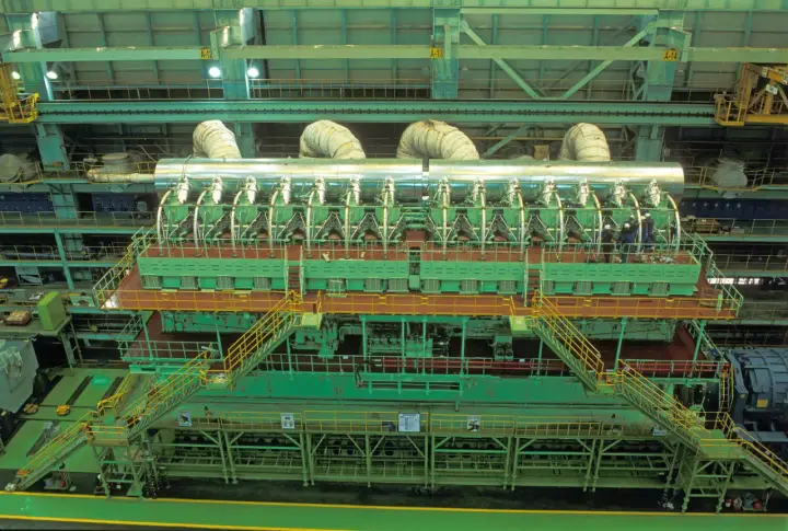 Vue aérienne d'un moteur de bateau massif, le plus gros moteur de bateau jamais construit, avec des ouvriers inspectant son imposante structure verte et argentée.
