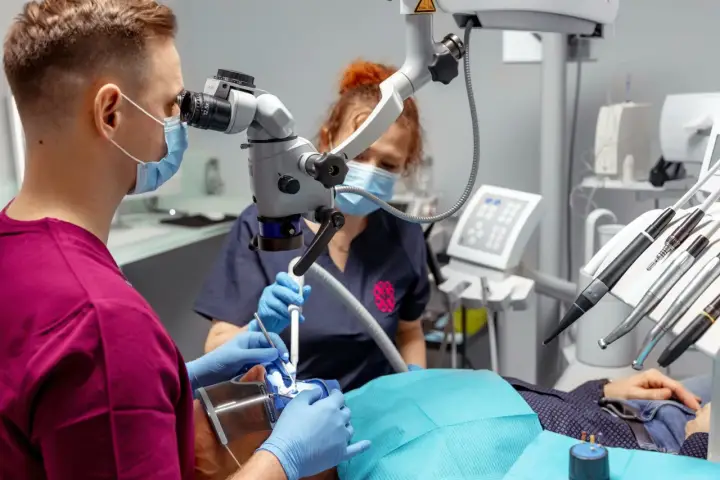 Stomatolog z mikroskopem precyzyjnie usuwa próchnicę z zęba pacjenta.