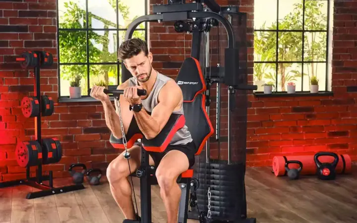 Mężczyzna ćwiczy biceps na domowej siłowni. Sprzęt i akcesoria, jak hantle i kettlebelle, to dowód na to, że polskie marki sportowe oferują wszystko, co potrzebne do treningu.