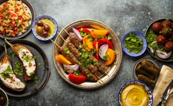 Un festin de plat méditerranéen : brochettes de viande, aubergines rôties, falafels, feuilles de vigne farcies, houmous et salade de couscous.