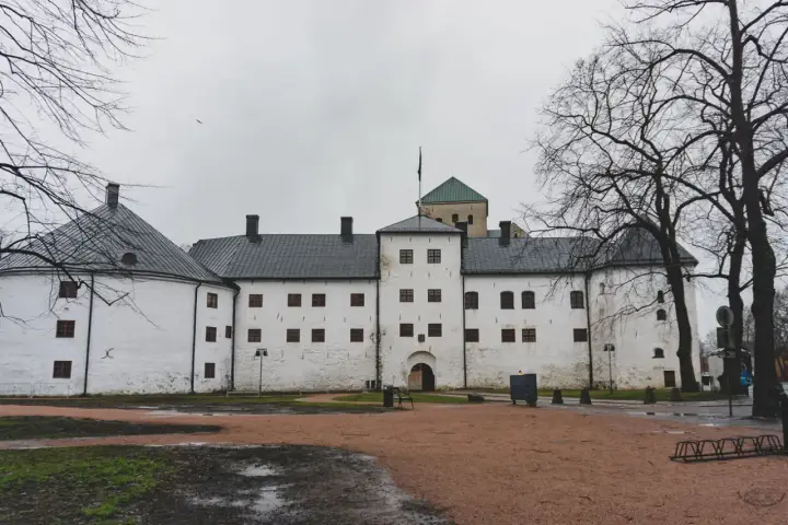 Biały zamek z wieżą i zielonym dachem, symbol najstarszego miasta w Finlandii.