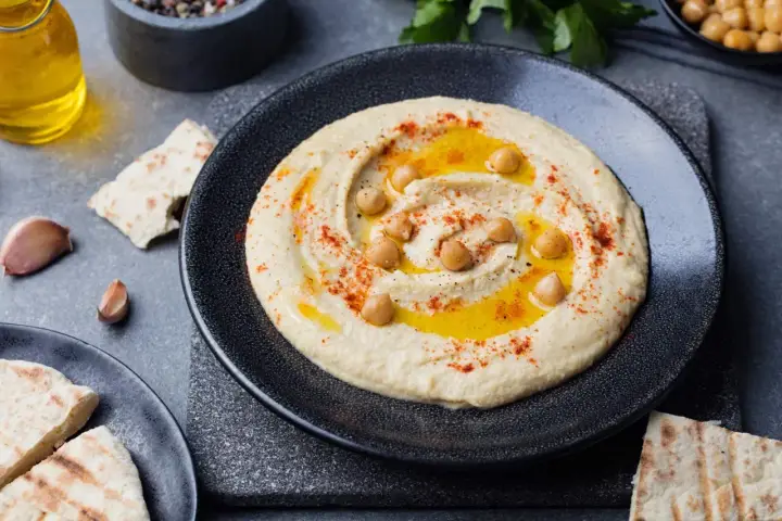 Pyszny, kremowy hummus co to jest? To pasta z ciecierzycy, oliwy, czosnku i przypraw, podana z pitą.