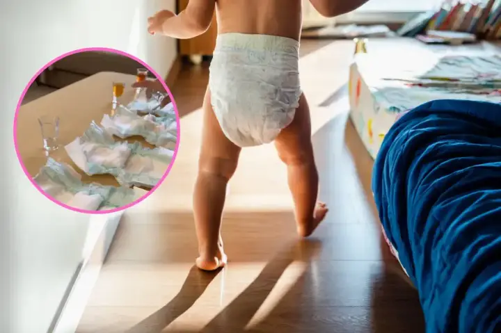 Dziecko w pieluszce idzie po pokoju. Na stole w okręgu leżą pieluchy i kieliszki.