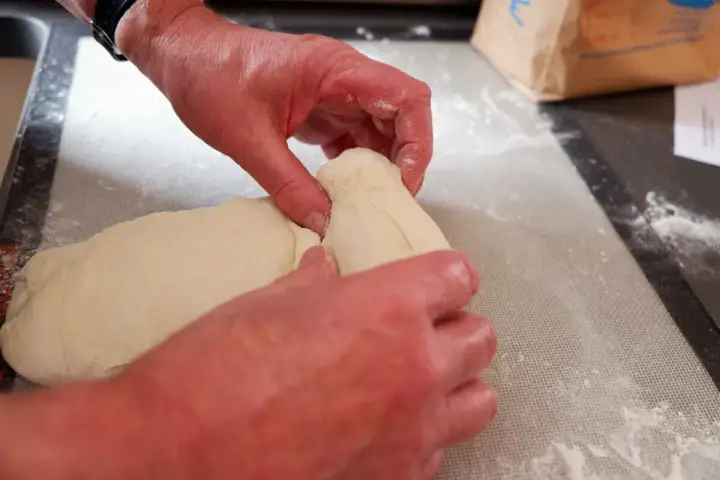 Mains travaillant la pâte à pain, étape d'autolyse. La pâte est souple et prête à être façonnée.