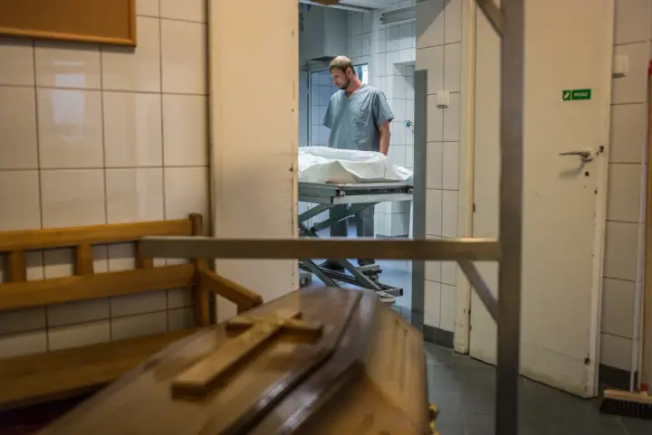 W prosektorium, po sekcji zwłok, pracownik pochyla się nad noszami. Czy po sekcji zwłok można otworzyć trumnę?