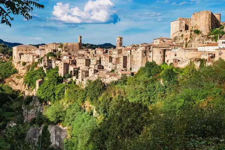 Un affascinante borgo toscano da visitare, arroccato su una rupe tufacea, con case in pietra e torri che si stagliano contro il cielo azzurro.