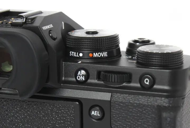 Część aparatu Fujifilm xt3 z pokrętłem wyboru trybu "STILL" i "MOVIE", przyciskiem "AF ON" i pokrętłem sterującym.