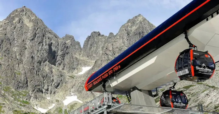 Kolejka linowa wjeżdża na skalne pleso, w tle majestatyczne szczyty Tatr.