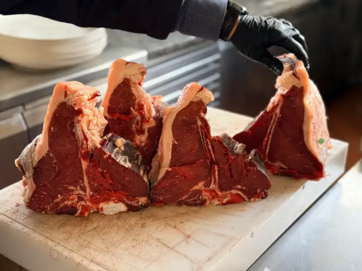 Maneggiare con cura la bistecca fiorentina a Firenze, pronta per essere grigliata.