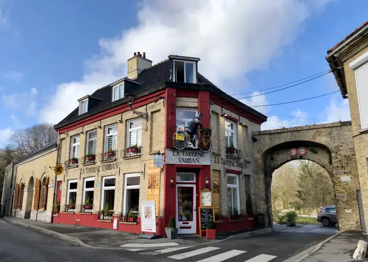 Façade de la Taverne Vauban à Bergues, avec une enseigne et une décoration de cycliste.