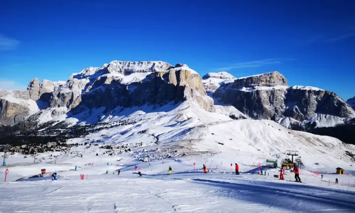 Piste innevate e maestose vette per decidere dove andare a sciare in Trentino. Sciatori e impianti di risalita animano il paesaggio.