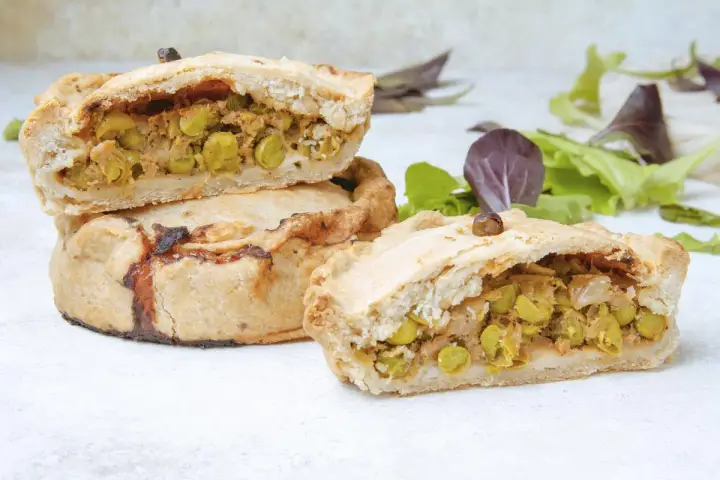 Empanadas mallorquinas rellenas de guisantes y carne, con una masa dorada y crujiente.