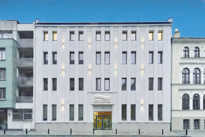 Nowoczesny, biały budynek kliniki Balticmed w Szczecinie z podświetlanym logo i oknami.