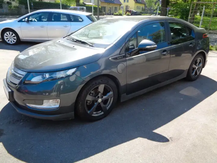 Ciemnoszary Chevrolet Volt stoi na parkingu. Obok niego widać srebrne kombi.
