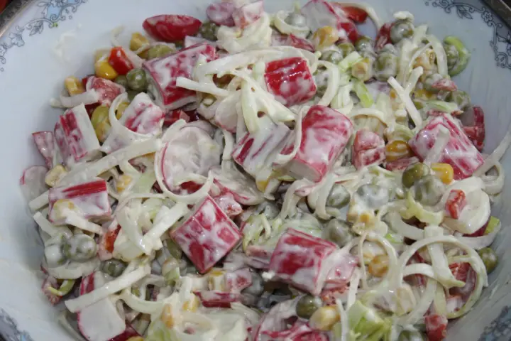 Pyszna sałatka z paluszkami surimi, groszkiem, kukurydzą i porem, polana kremowym sosem.