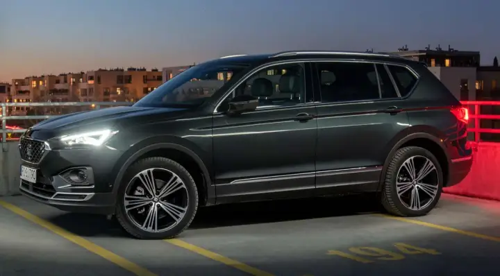 Ciemnozielony SUV, jeden z najbardziej polecanych samochodów 7-osobowych, zaparkowany na dachu parkingu nocą.