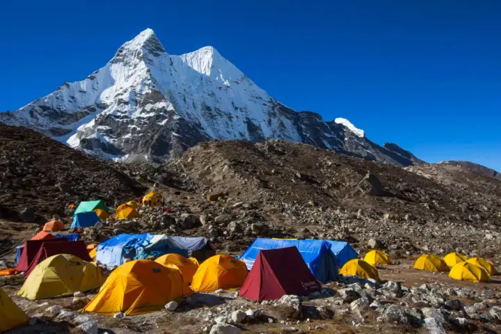 Obóz pod majestatycznym szczytem Karakorum. Kolorowe namioty rozstawione na kamienistym zboczu, gotowe na przyjęcie alpinistów.