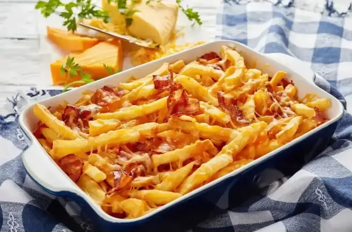 Zapiekane frytki z serem i chrupiącym boczkiem, podane w niebieskiej brytfance na kratkowanym obrusie.