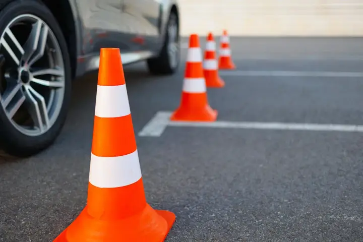 Pomarańczowe pachołki na placu manewrowym. Zastanawiasz się, jakie prawo jazdy potrzebne na autolawetę?