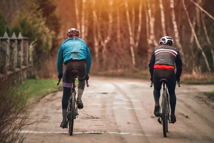Dwóch rowerzystów w jesiennych strojach, idealnych na 15 stopni. Lekka kurtka i długie spodenki to dobry wybór na przejażdżkę.