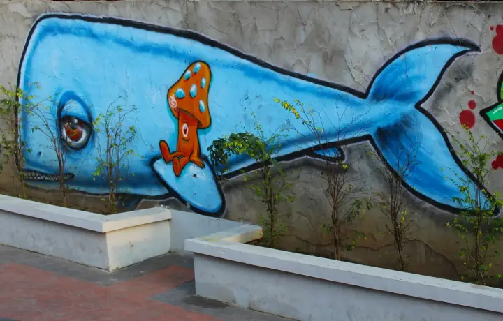 Niebieski wieloryb z grzybkiem na grzbiecie. Inspiracja, jak zrobić mural na kartce, w miejskim krajobrazie.