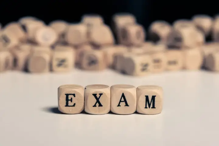 Drewniane kostki z literami tworzą napis "EXAM". Zastanawiasz się, na jakim poziomie jest matura podstawowa z angielskiego?