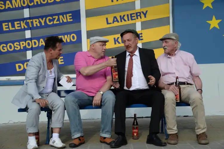 Czterech mężczyzn siedzi na ławce, pijąc mamrota.