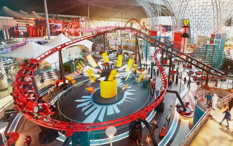 Wesołe miasteczko Ferrari World w Dubaju z kolejką górską i karuzelami w akcji.