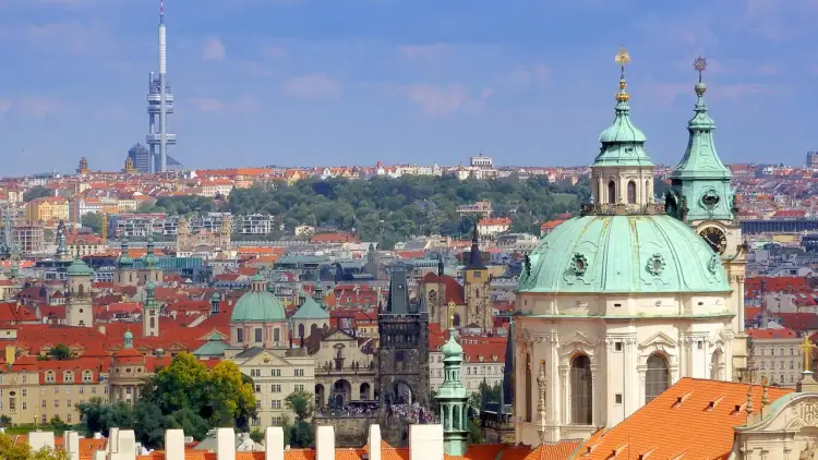 Widok na Pragę z zielonymi kopułami i charakterystyczną wieżą telewizyjną w tle.