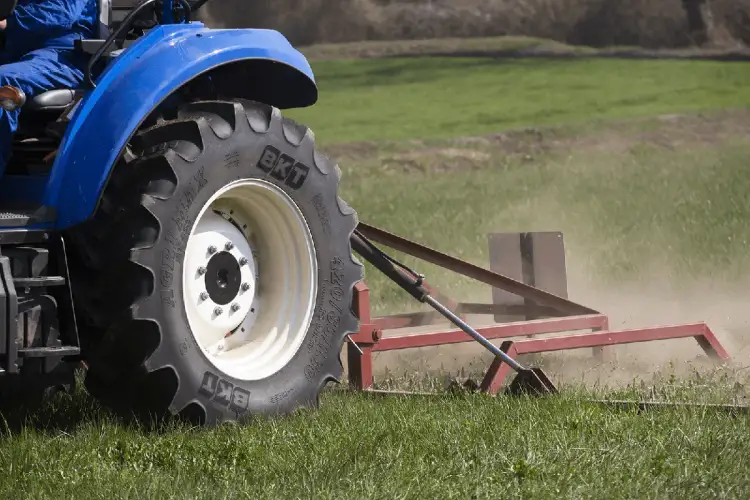 Ciągnik rolniczy z wielką oponą BKT AgriMax pracuje na polu. Zastanawiasz się, ile waży opona rolnicza?