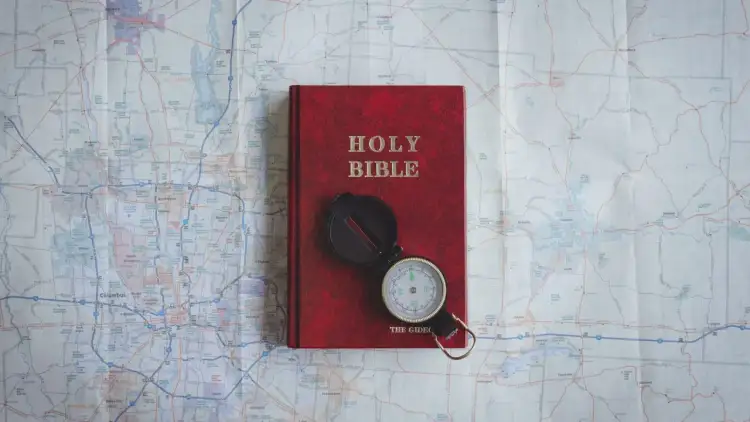 Czerwona Biblia i kompas na mapie. Pismo Święte wskazuje drogę, jak nie cudzołożyć, co to znaczy żyć w zgodzie z Bogiem.