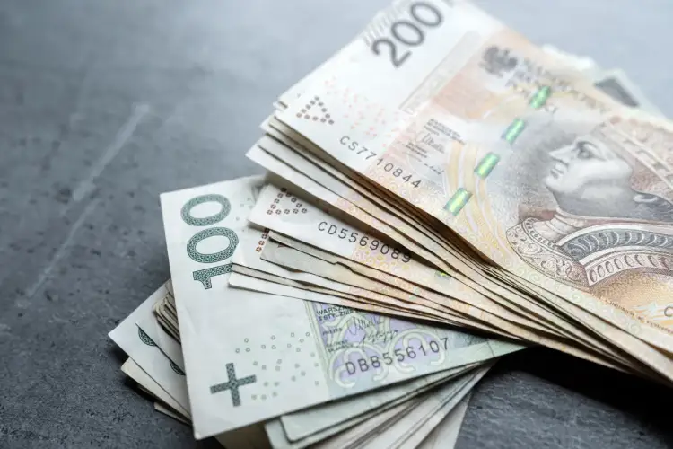 Stos banknotów 100 i 200 zł, symbolizujących oszczędności na wcześniejszą emeryturę.