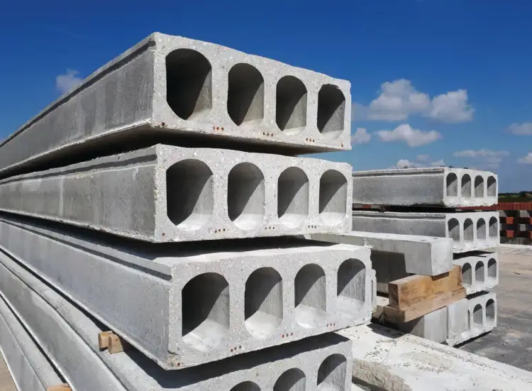 Stos betonowych płyt stropowych kanałowych pod błękitnym niebem. Gotowe do budowy domu.