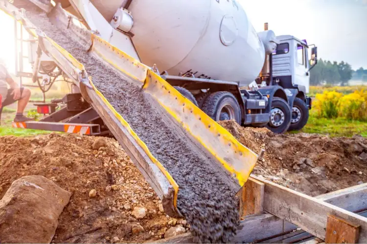 Betoniarka wylewa beton do szalunku. Pytanie brzmi, w jakich temperaturach można murować, aby zapewnić trwałość konstrukcji.