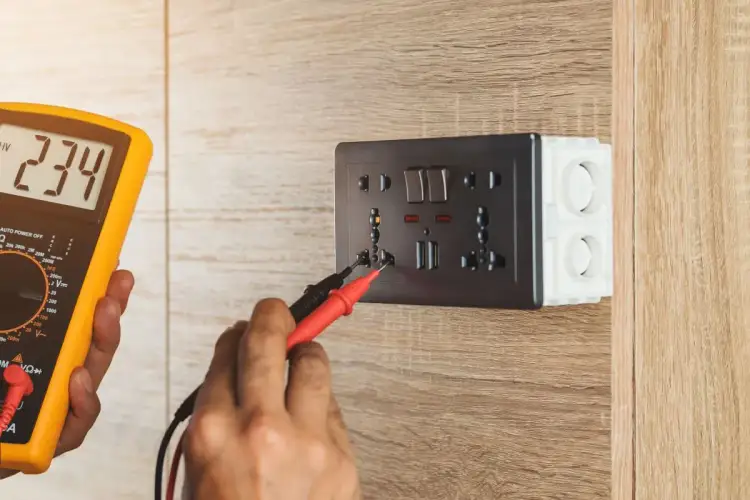 Elektryk sprawdza napięcie w gniazdku za pomocą miernika. Oto jak zmierzyć miernikiem baterie, lub napięcie w sieci.