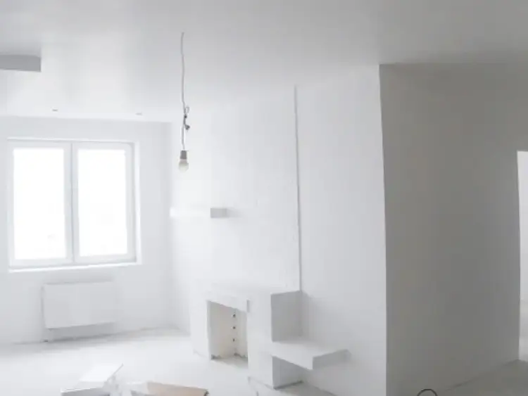 Nowe, ciekawe zabudowy z płyt gipsowych tworzą nowoczesny kominek i półki. Pokój w trakcie remontu.