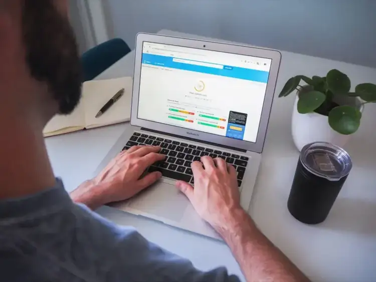Osoba pracuje na laptopie, na ekranie którego widoczny jest wynik testu prędkości strony internetowej.