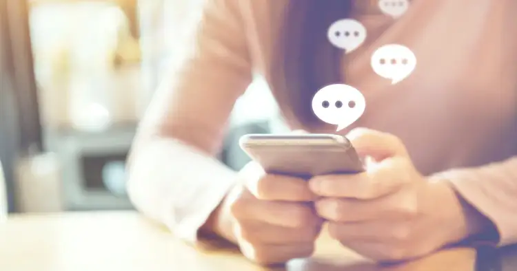 Osoba pisze na telefonie, a nad nim pojawiają się dymki czatu. Dowiedz się, jak włączyć dymki czatu w Messengerze, by rozmowy były jeszcze bardziej widoczne.
