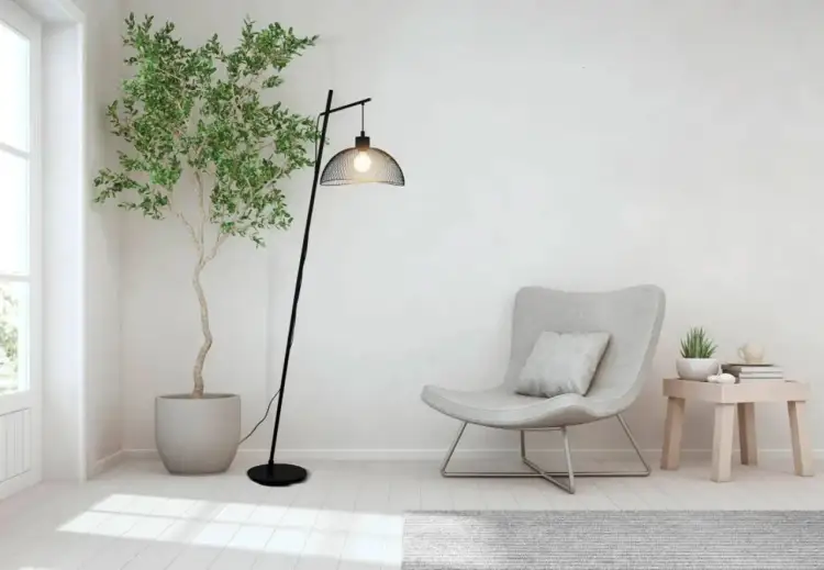 Nowoczesna, czarna stojąca lampa led z metalowym kloszem, oświetlająca przytulny kącik z fotelem i rośliną.
