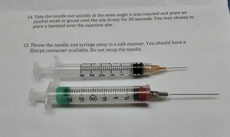 Dwie strzykawki z igłami, jedna z pomarańczową osłonką, druga z czerwoną. Pokazują, jaka igła do zastrzyku domięśniowego.