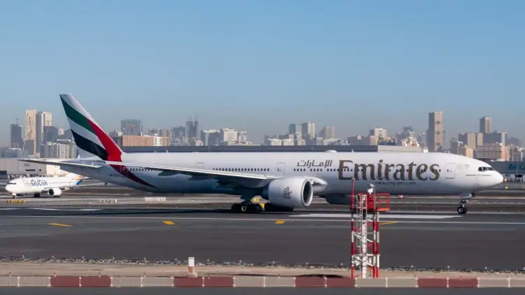 Samolot Emirates na płycie lotniska, w tle panorama Dubaju. Zastanawiasz się, ile trwa lot Warszawa Dubaj?