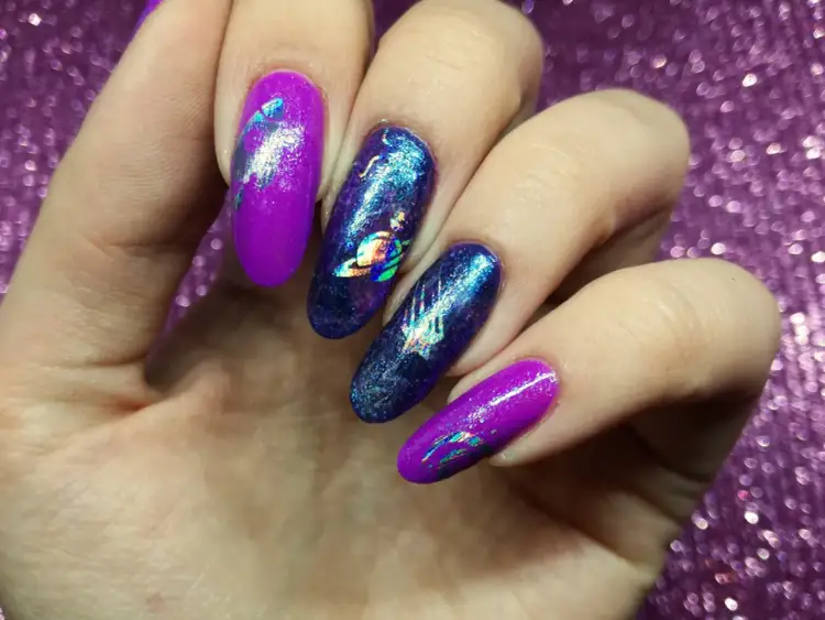 Kosmiczne paznokcie z folią transferową w odcieniach fioletu i granatu. Na jednym z paznokci widoczny Saturn.