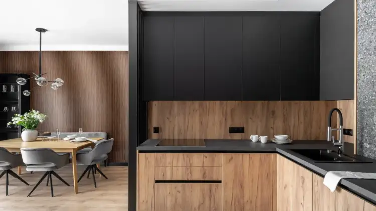 Nowoczesna kuchnia z drewnianymi panelami ściennymi, czarnymi szafkami i jadalnią. Dowiedz się, jak odnowić panele ścienne w kuchni, by nadać jej nowy wygląd.